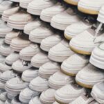 A large collection of white sneakers neatly arranged in a shoe store display.